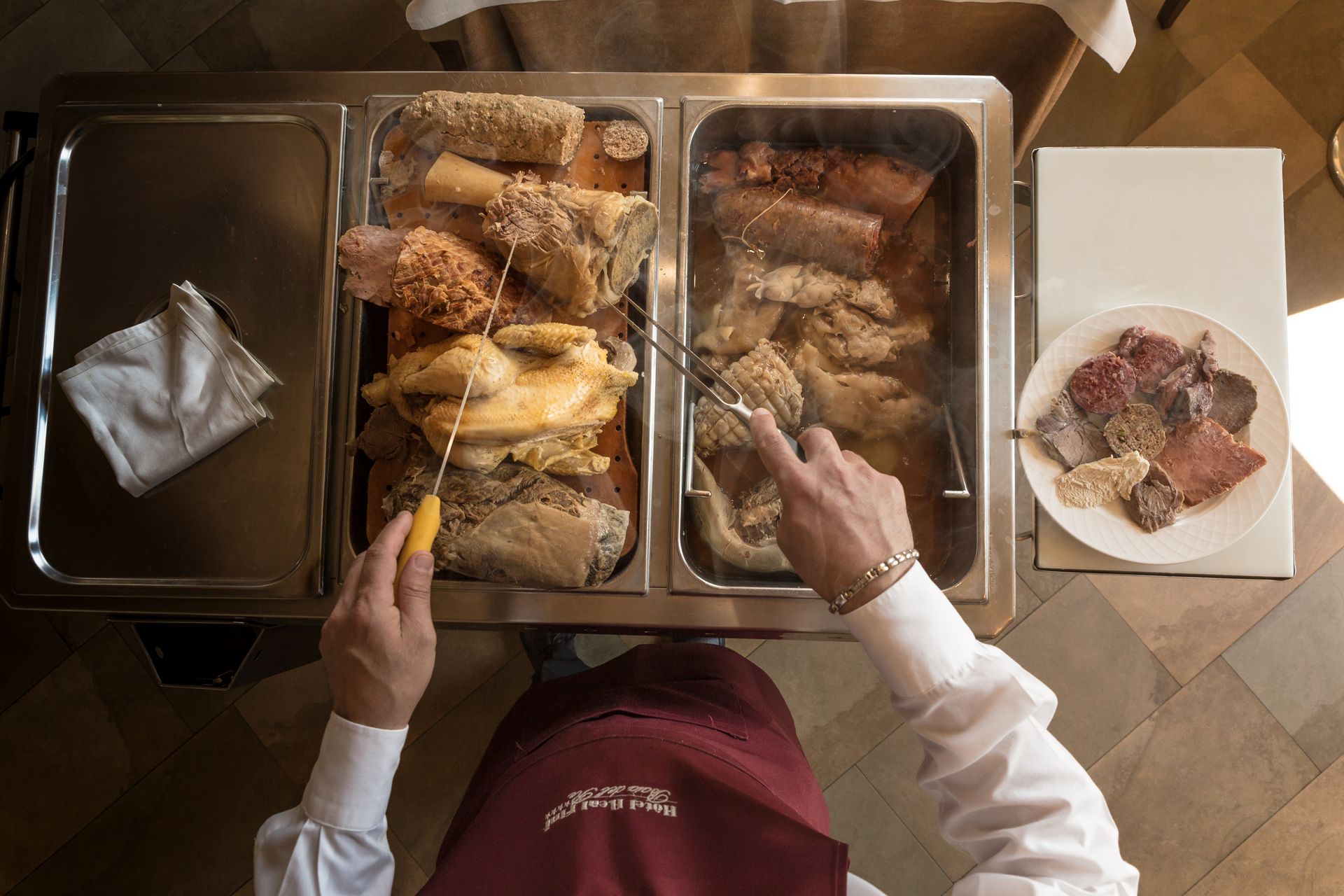 Vue de dessus de deux personnes servant du poulet depuis des plateaux de buffet en acier inoxydable vers une assiette