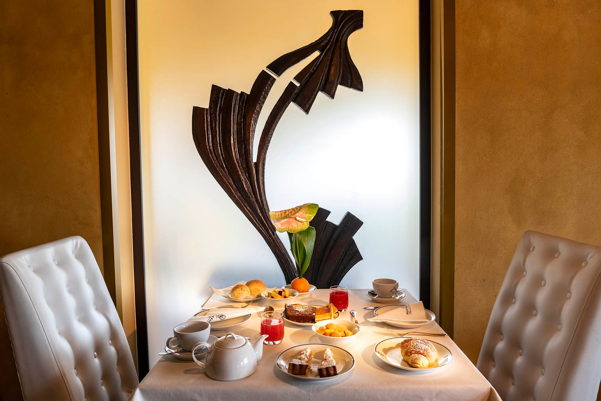 Élégante table à manger dressée avec de la vaisselle pour le petit-déjeuner et une sculpture abstraite noire