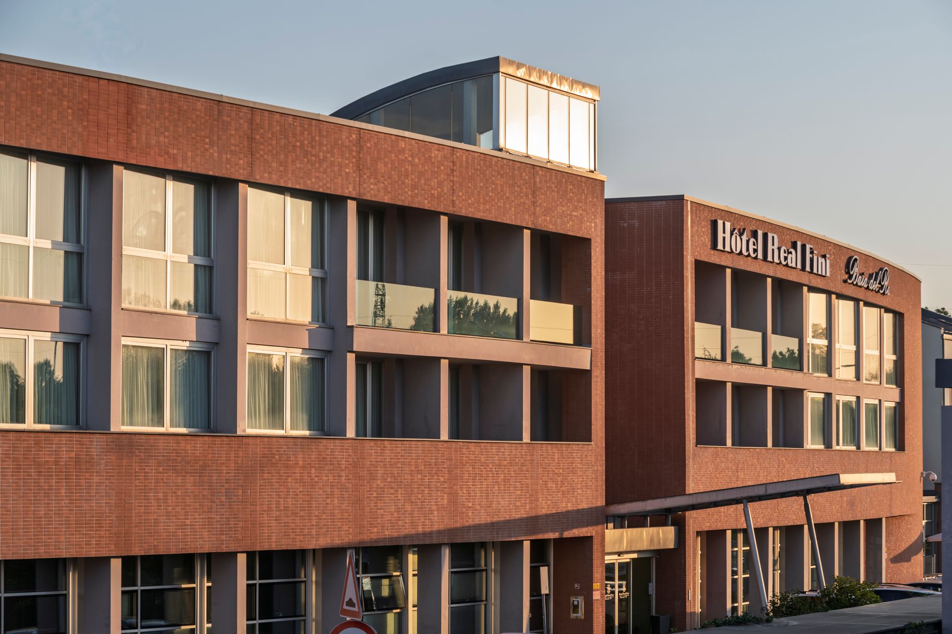 Hotel Real Fini Baia del Re et en verre, baigné par la douce lumière du coucher de soleil, avec une enseigne sur le toit