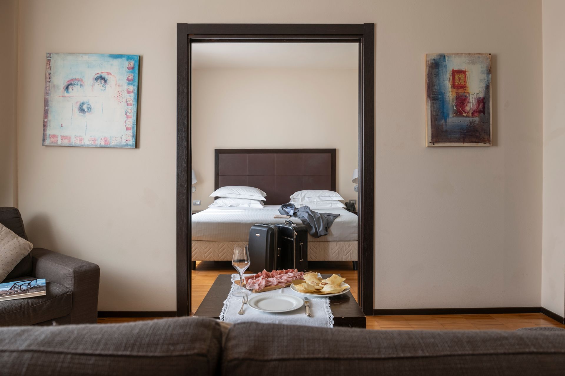 Vue du salon à travers la porte donnant sur un lit soigneusement fait dans la chambre du fond