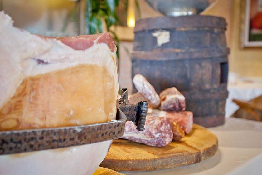 Meule de fromage et charcuterie sur une table avec un tonneau en bois en arrière-plan