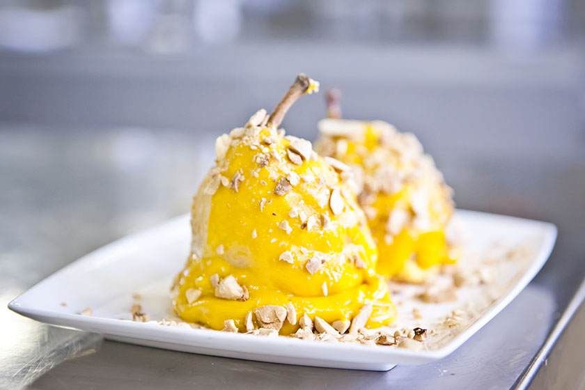 Deux petits monticules de dessert jaunes recouverts de miettes sur une assiette blanche, sur un comptoir flou.