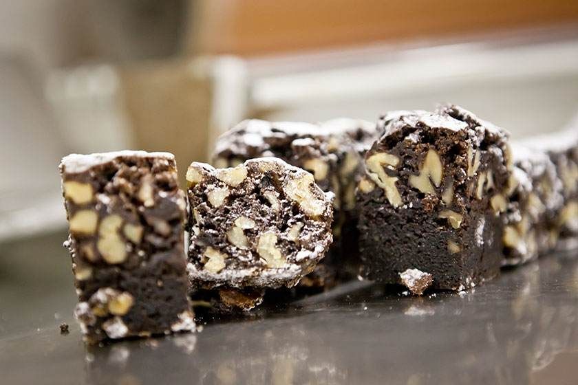 Carrés de chocolat aux noix présentés sur un plateau, avec des noix hachées visibles dans les morceaux.