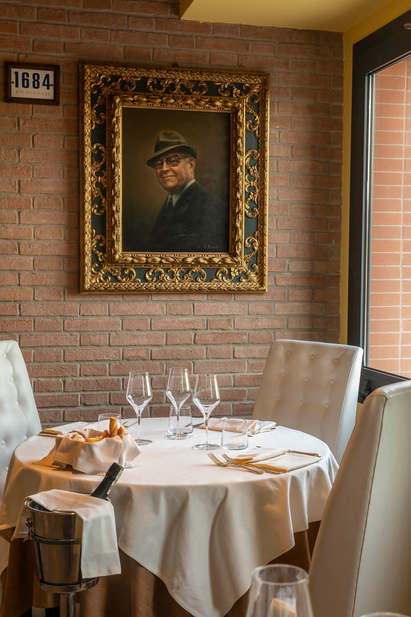 Cozy dining table set for two beneath a framed portrait on a brick wall