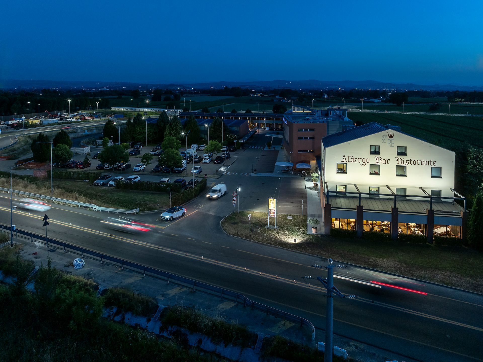 Vue nocturne d'Hotel Real Fini Baia del Re illuminé en bordure d'une autoroute très fréquentée