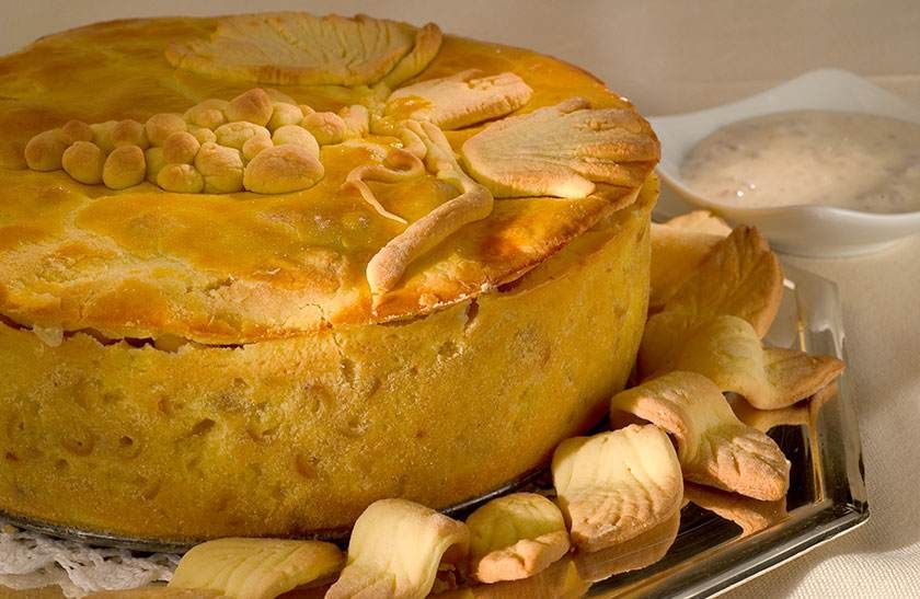 Dessert rond cuit au four, garni de tranches de pommes et de noix, servi avec un bol de crème.