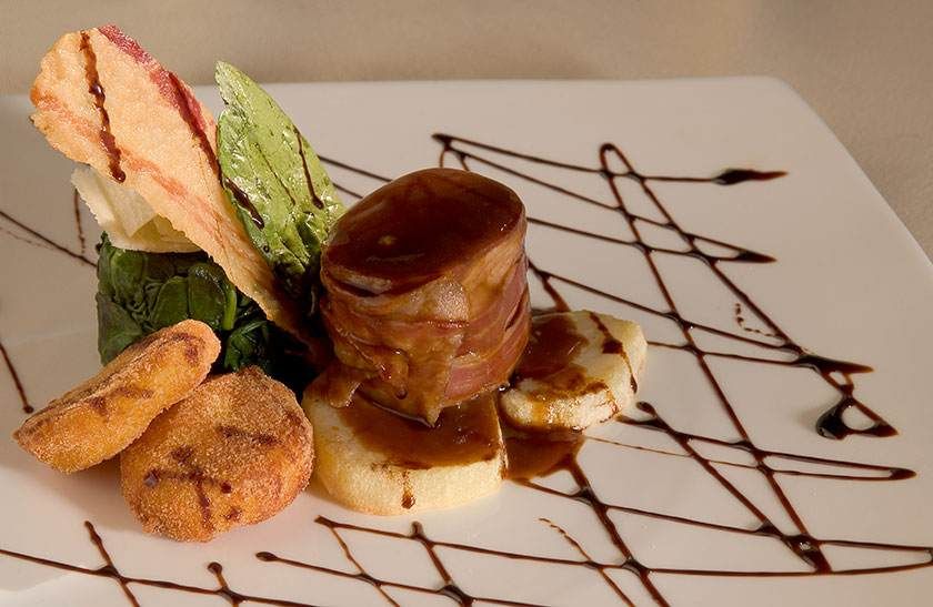 Assiette de desserts gourmands avec filet de chocolat, mousse au caramel, biscuits et garniture de menthe.