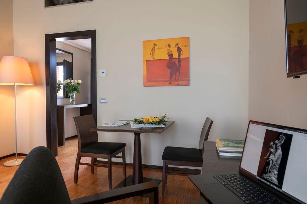 Cozy dining nook with table, chairs, lamp, wall art, and a laptop on a desk in the foreground