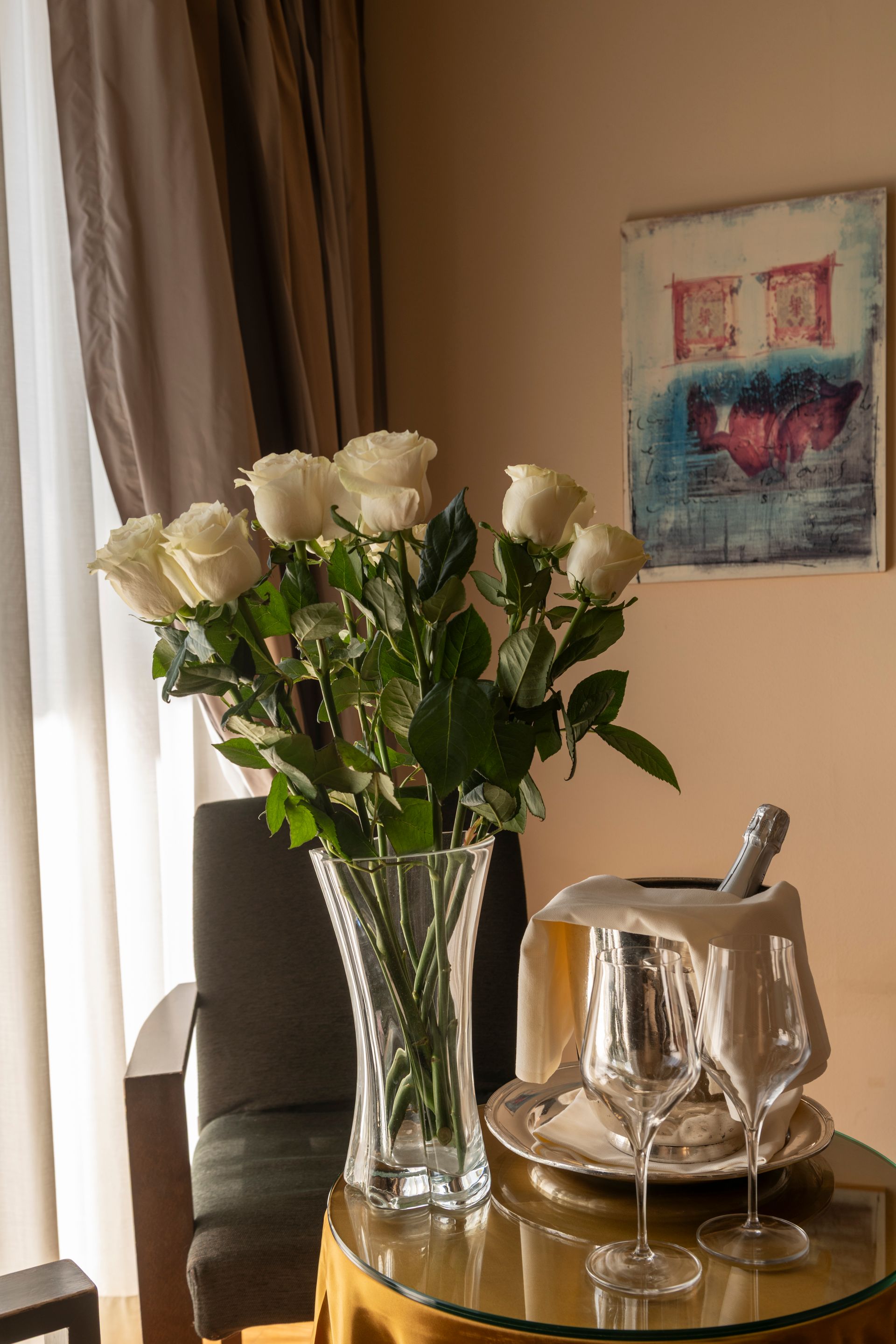 Rose bianche in un vaso su un tavolo accanto a un secchiello per il ghiaccio d'argento in una stanza illuminata