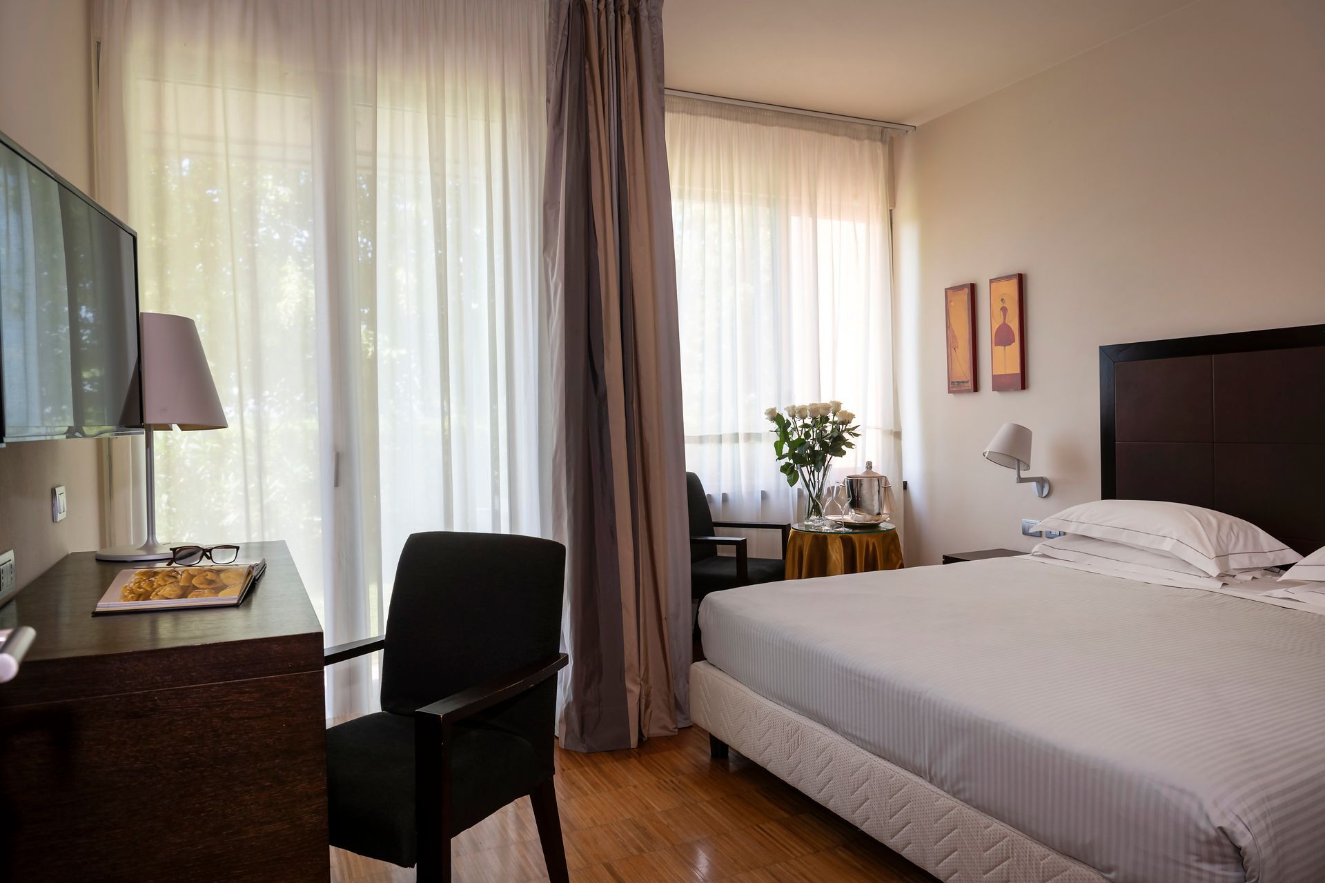 Camera da letto compatta con letto, scrivania, sedia e ampie finestre con tende