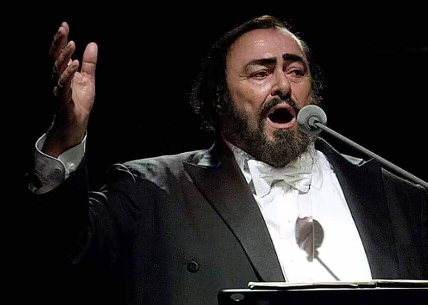 Chanteuse d'opéra en smoking sombre chantant dans un micro, une main levée sur scène