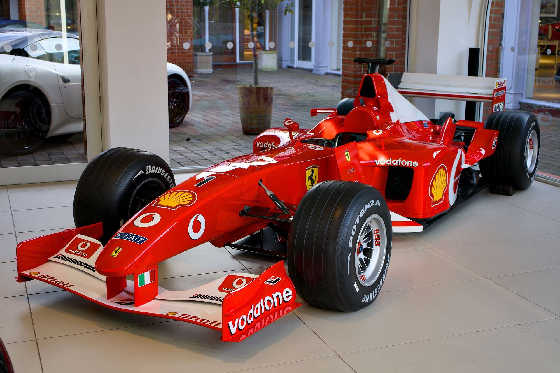 Auto da corsa Ferrari di Formula 1 rosso esposto al chiuso, visto dal davanti a sinistra.
