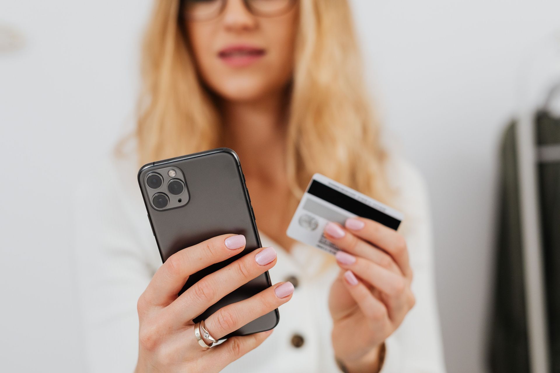 Woman holding a smartphone and credit card, suggesting an online purchase or payment