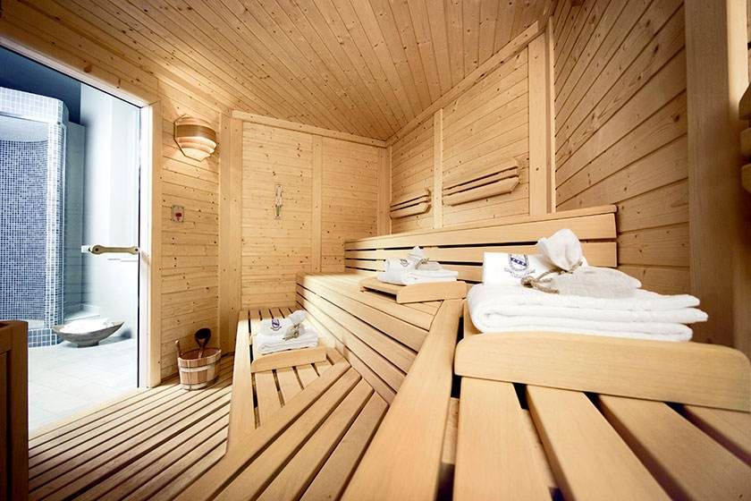 Sauna rivestita in legno, con panche, asciugamani e luci calde del centro benessere del nostro hotel a Modena