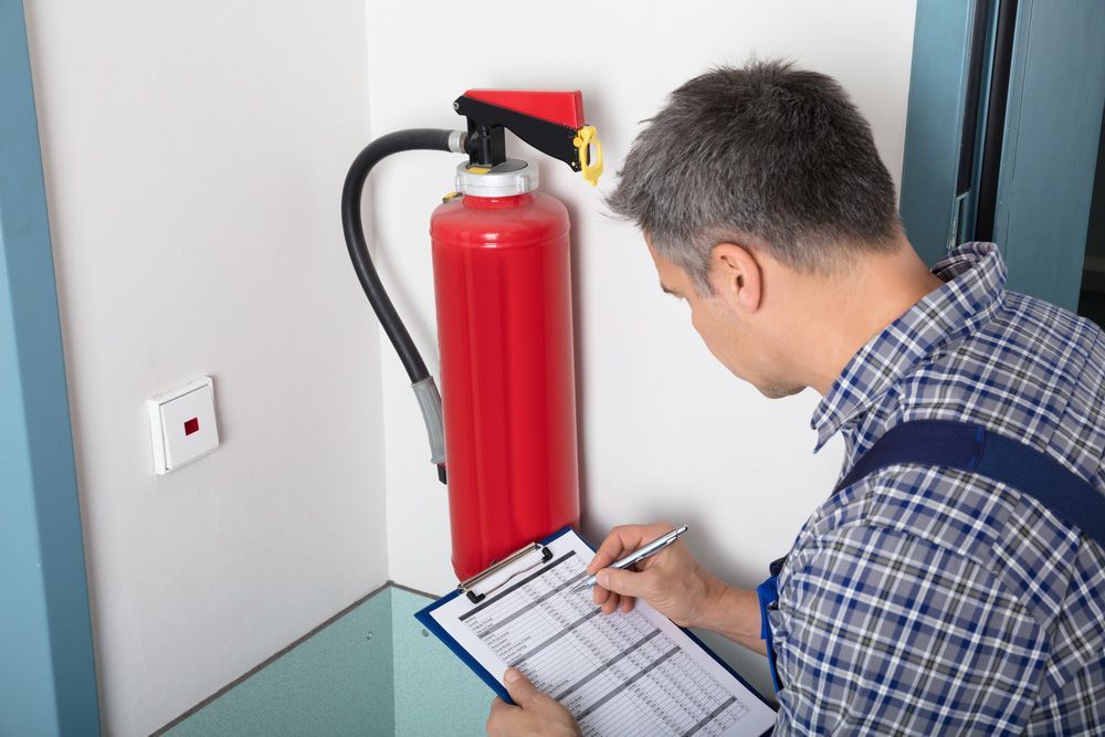 Man Inspecting a Red Fire Extinguisher and Checklist — Pasiv Fire in Wollongong, NSW