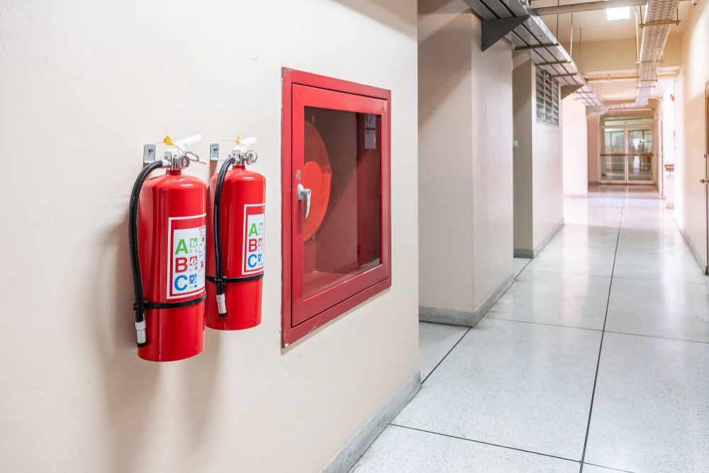 Fire Extinguishers and a Red Fire Hose Cabinet in a Clean Hallway — Pasiv Fire in Wollongong, NSW