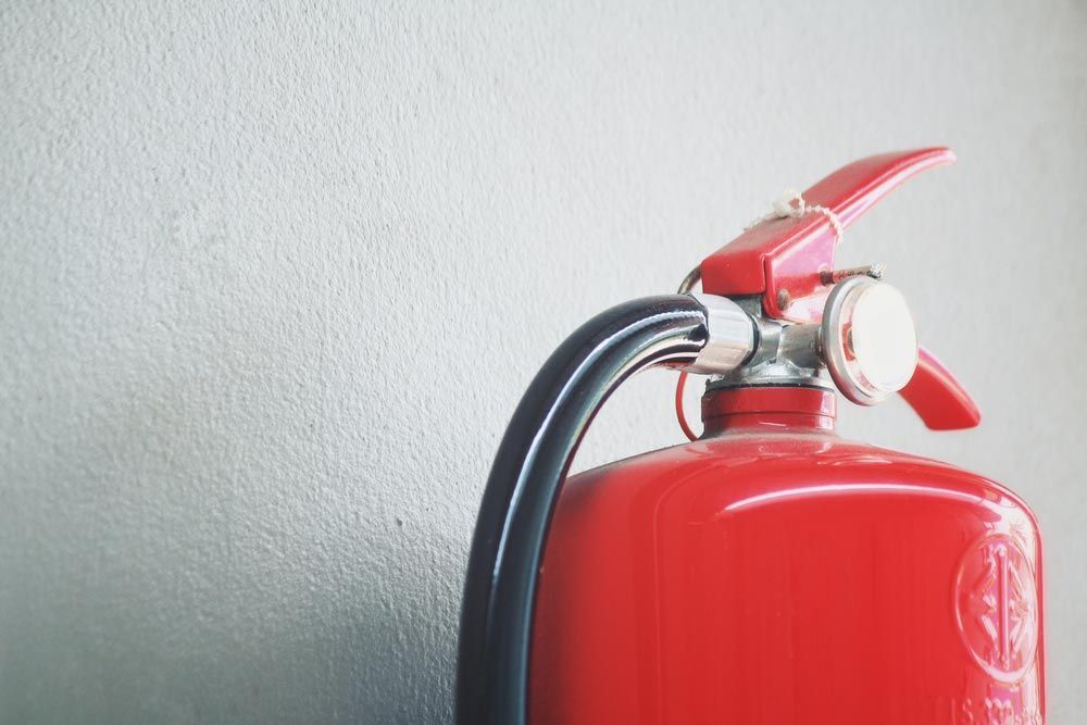 Red Fire Extinguisher Mounted Against a Light Gray Wall — Pasiv Fire in Wollongong, NSW