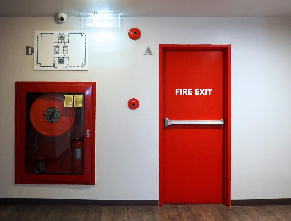 Hallway With Red Fire Hose Cabinet and Red Fire Exit Door — Pasiv Fire in Wollongong, NSW