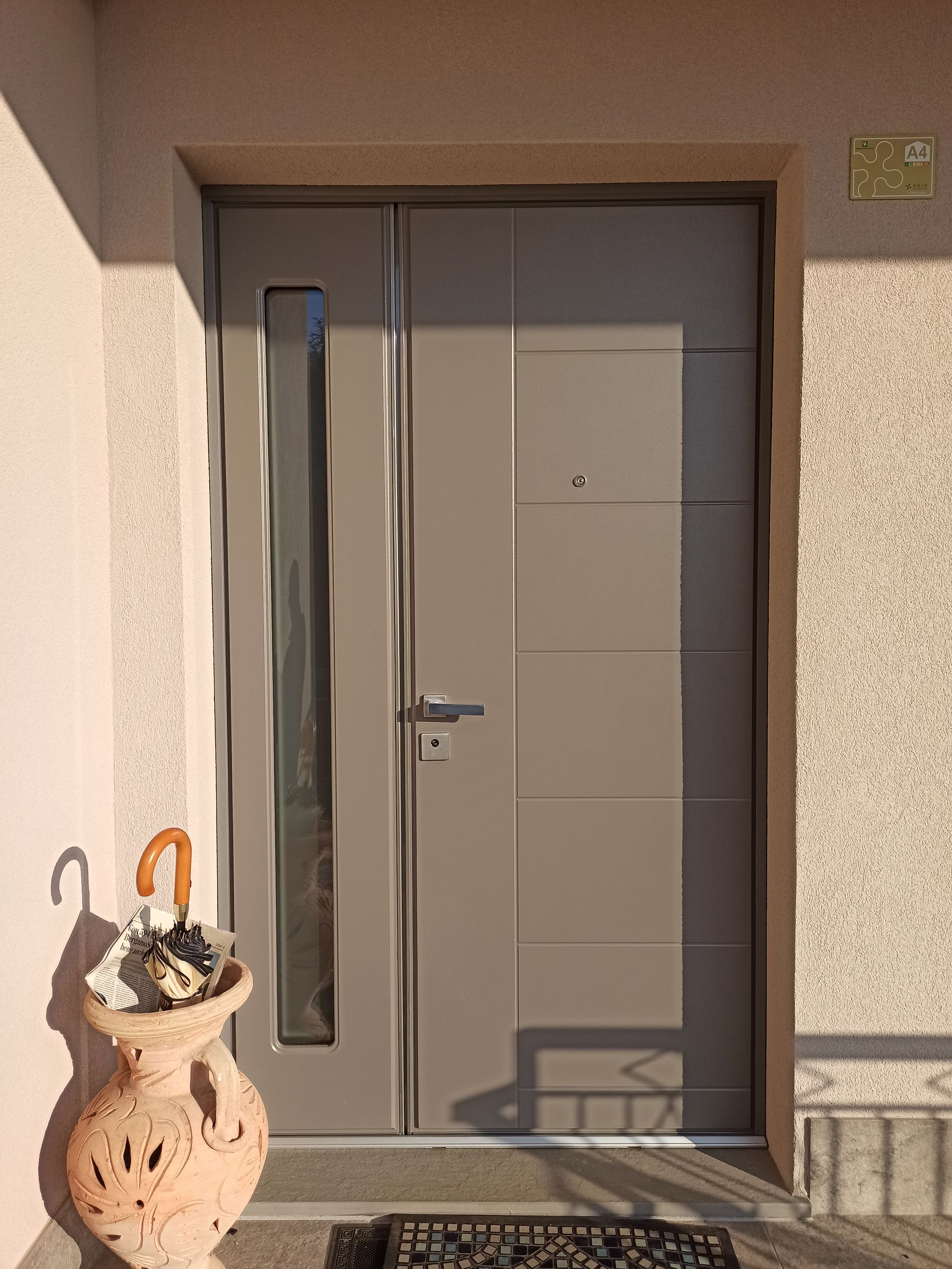 Porta rossa con pannelli rettangolari in un corridoio beige accanto a una ringhiera in vetro.