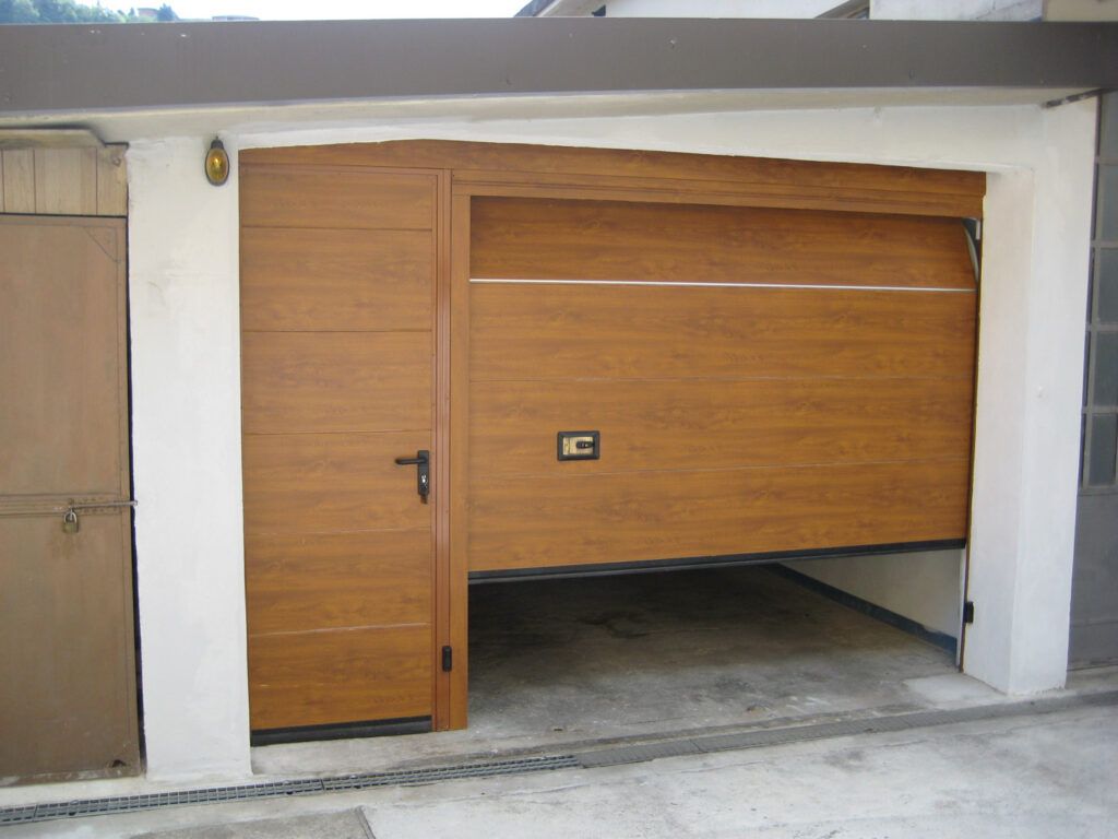 Porta da garage in legno parzialmente aperta in una parete esterna bianca