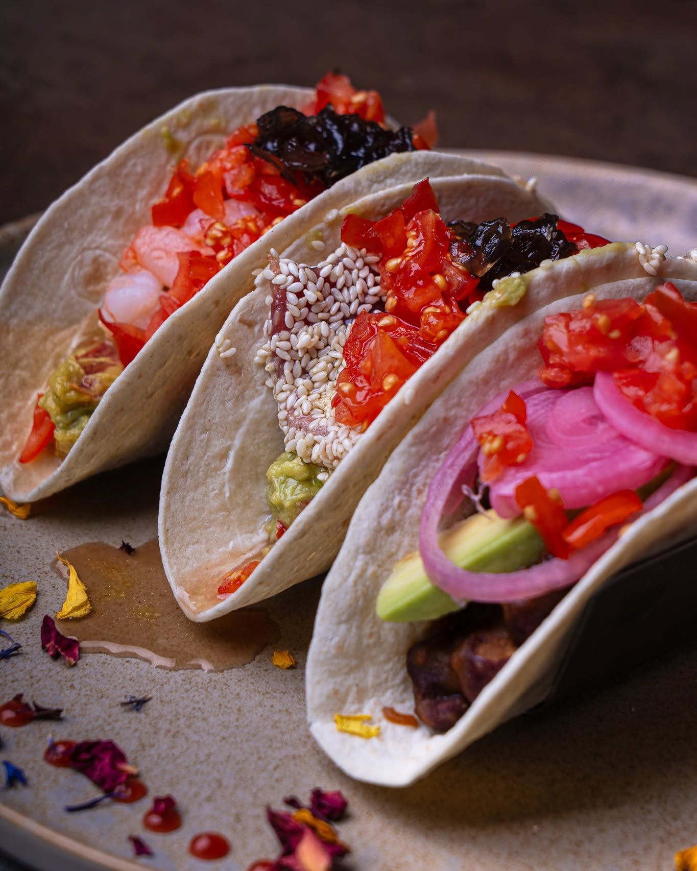 Tre tacos con condimenti colorati su un piatto, tra cui salsa, cipolle sottaceto e verdure