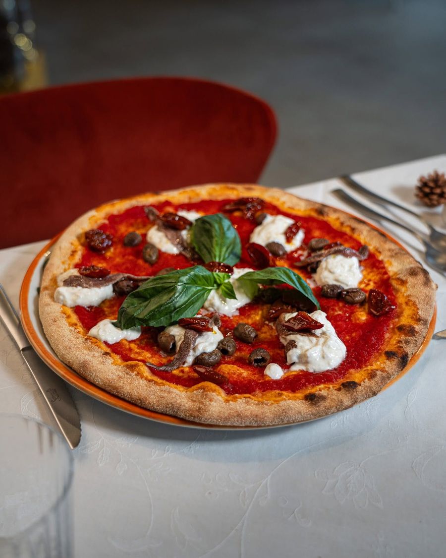 Pizza Margherita con basilico e formaggio fuso su un tavolo, servita su un piatto in un ristorante