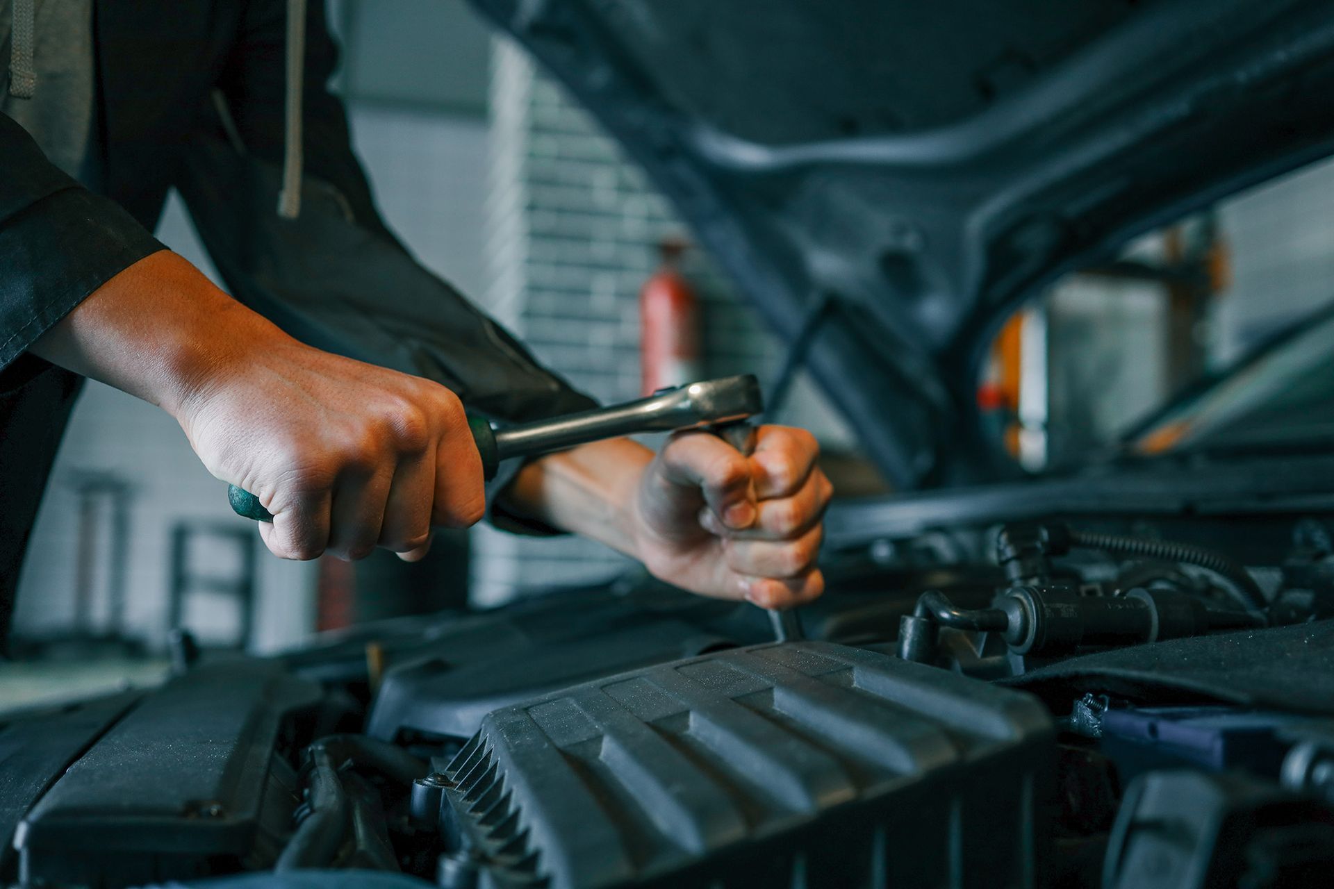 Mechanic using a wrench to tighten a car engine part in a garage