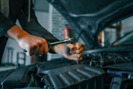 Mechanic using a wrench to work on a car engine in a garage