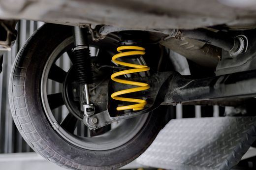 Close-up of a car wheel suspension with a bright yellow coil spring and shock absorber