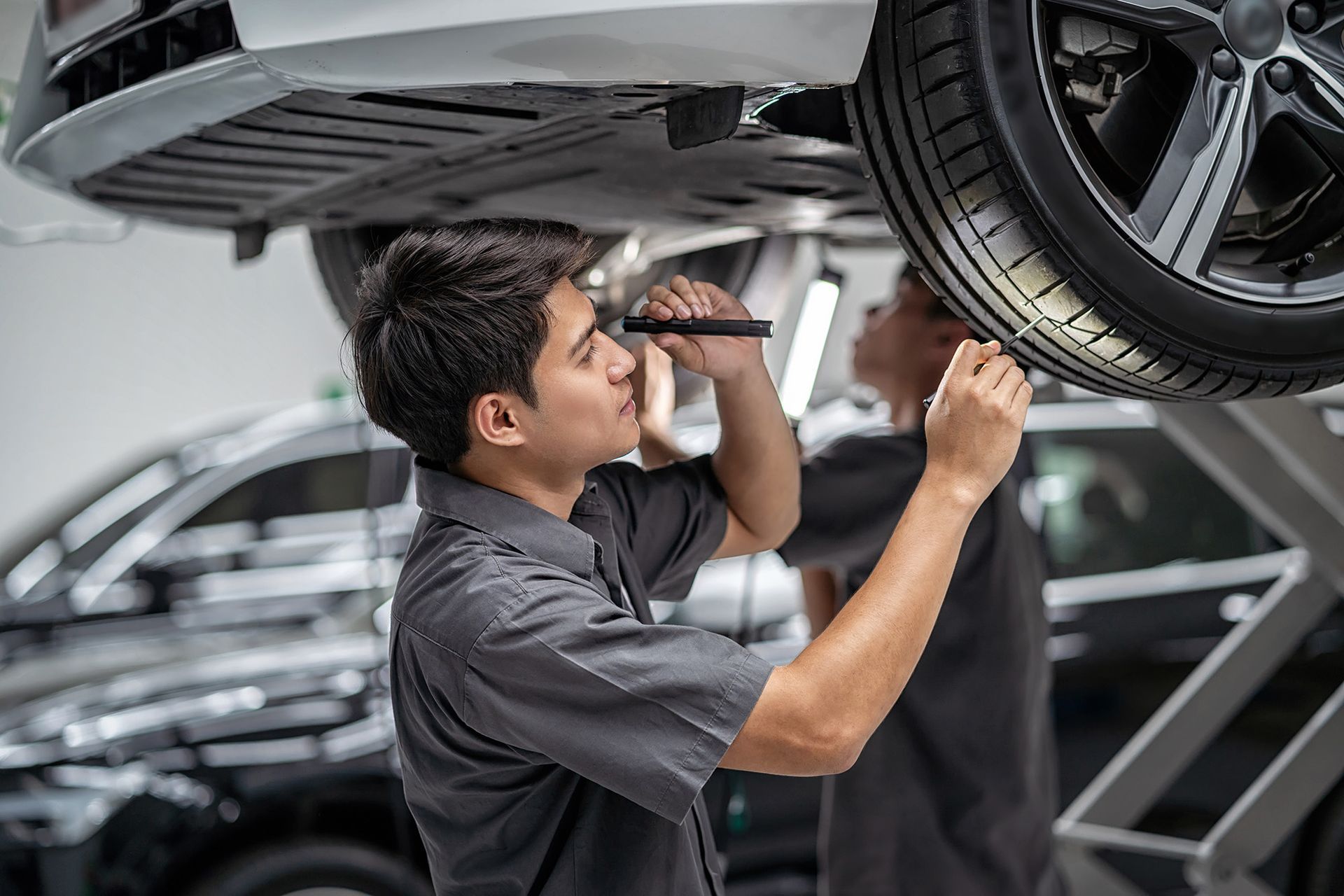 Mechanic inspecting the underside of a car in a repair shop
