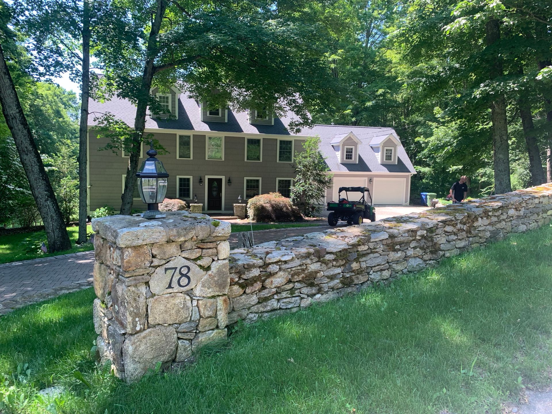 Stone wall with house number 78, a two-story home, and a golf cart on the driveway.