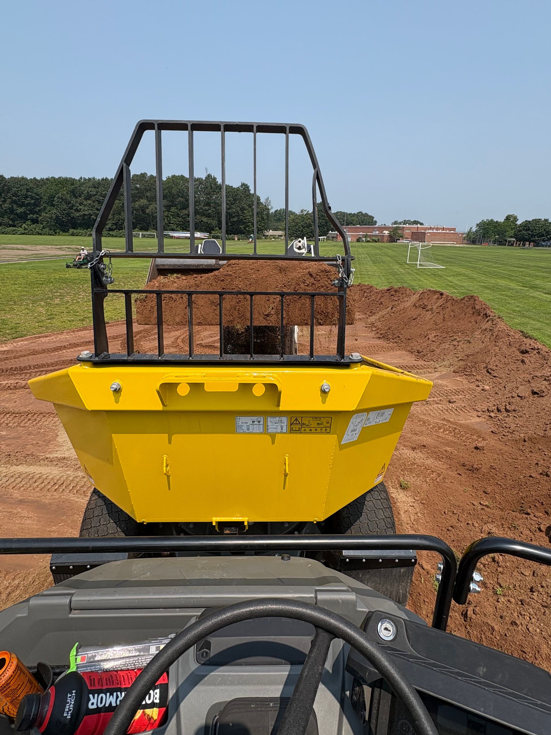 Yellow tractor with a bucket filled with dirt, working outdoors.