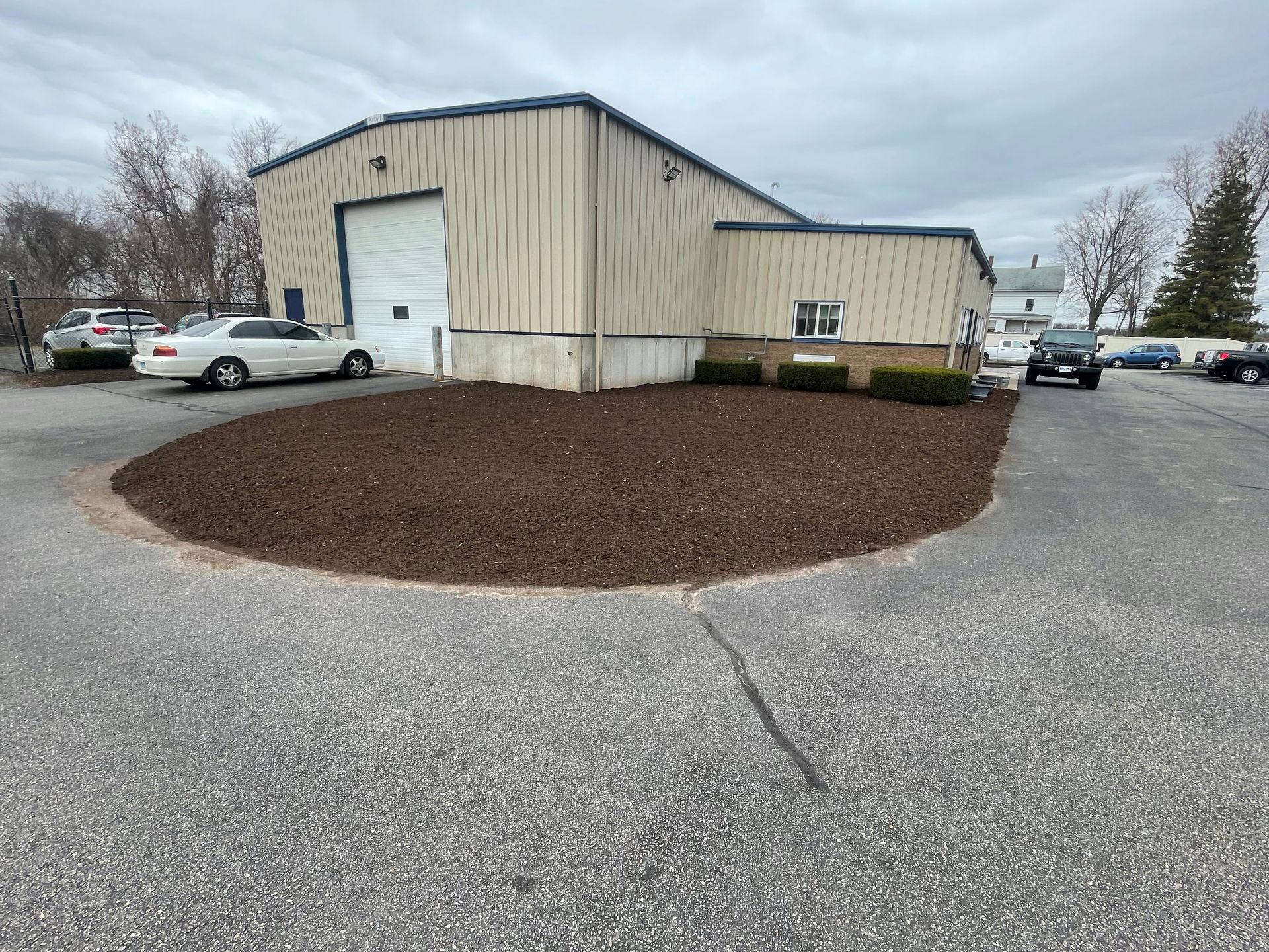 Exterior view of a commercial building with a gravel parking lot and a mulch bed.
