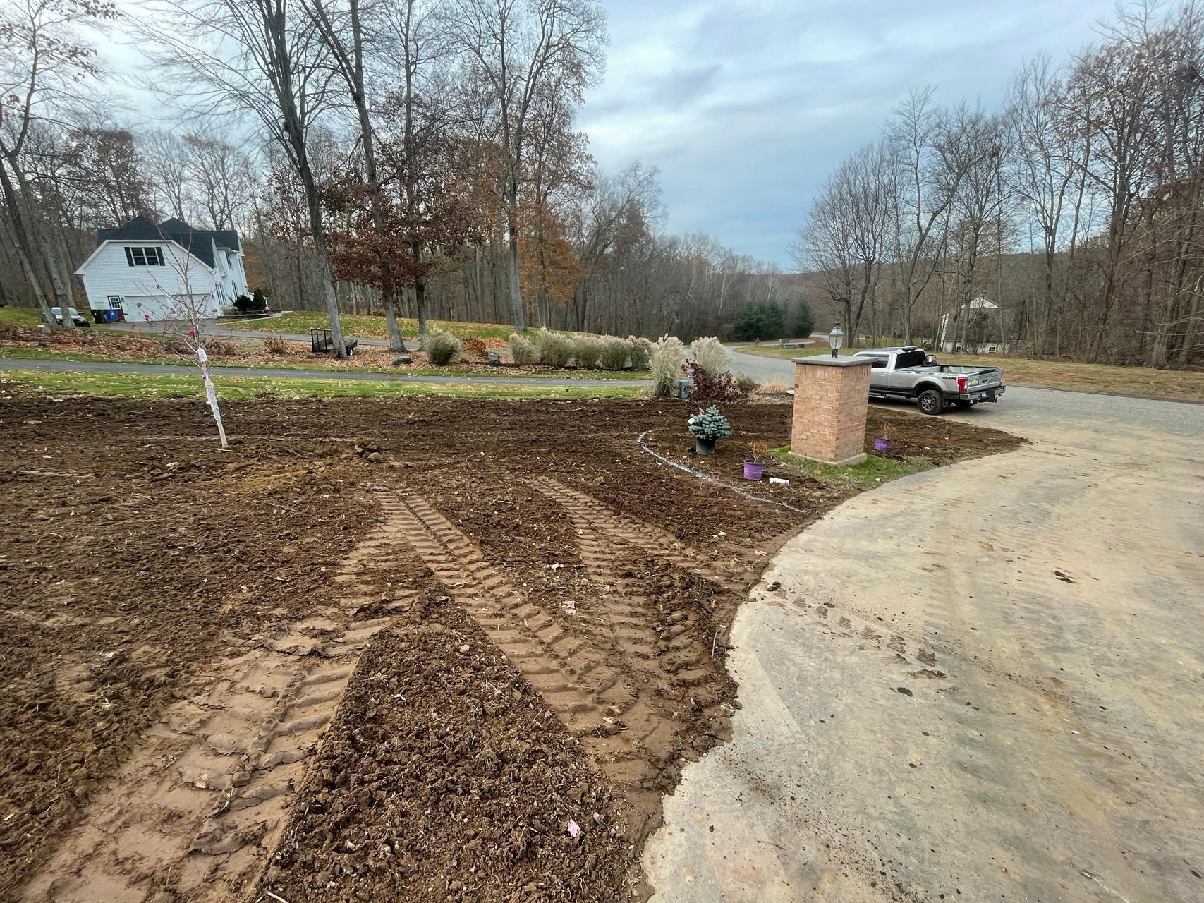Freshly graded dirt beside a curved driveway, with a truck and house in the background