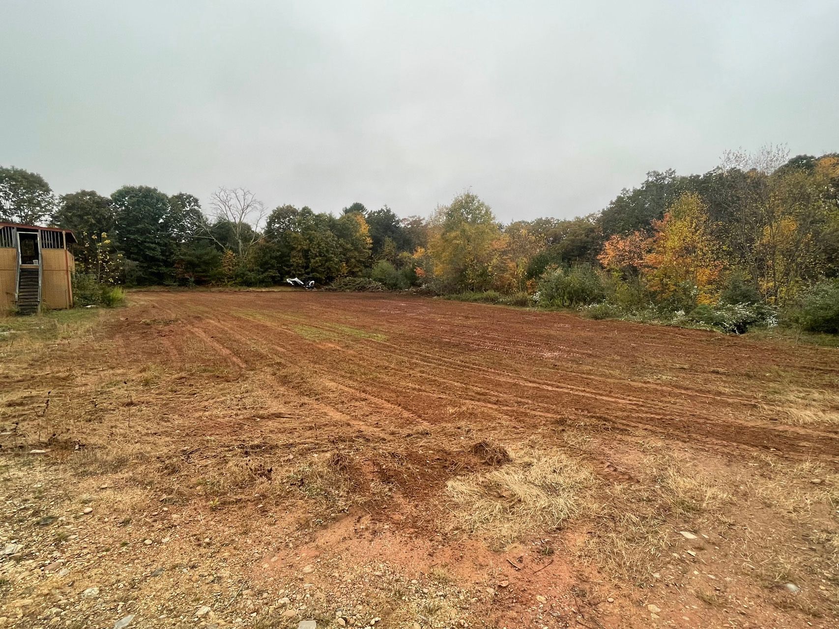 Freshly plowed field with a tree line in autumn under an overcast sky