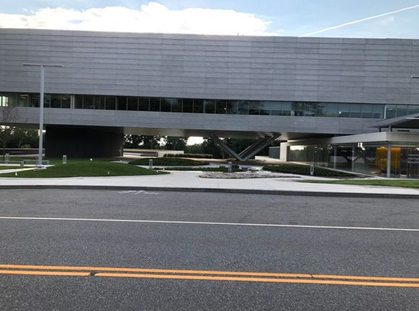 Modern gray building with horizontal windows and a parking lot in front