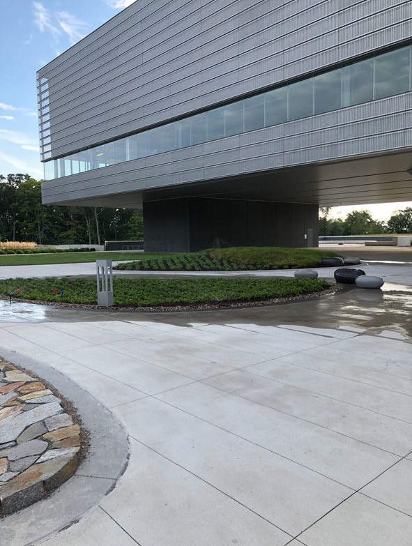 Modern glass-and-concrete building with landscaped walkway and open plaza outdoors