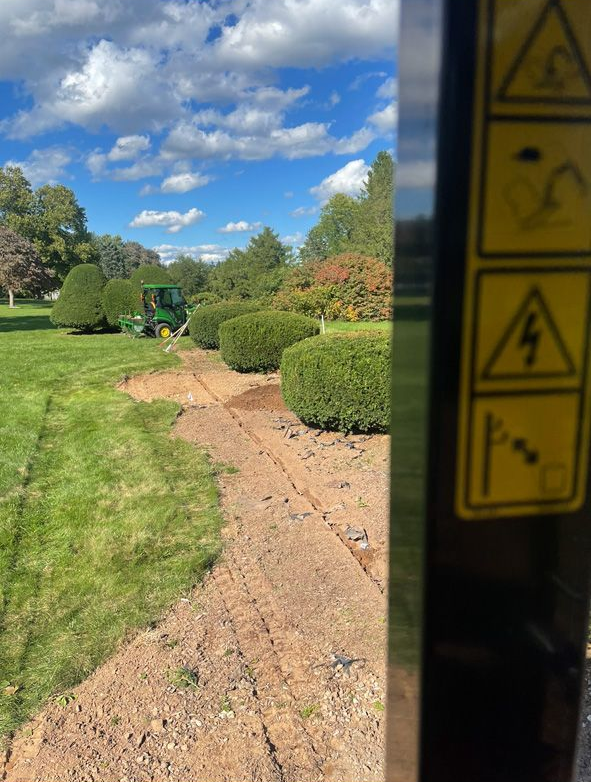 Gravel path through a green garden under a blue sky, viewed past a dark doorway with warning stickers.