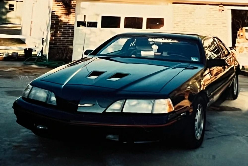 Black convertible sports car parked in a driveway at sunset