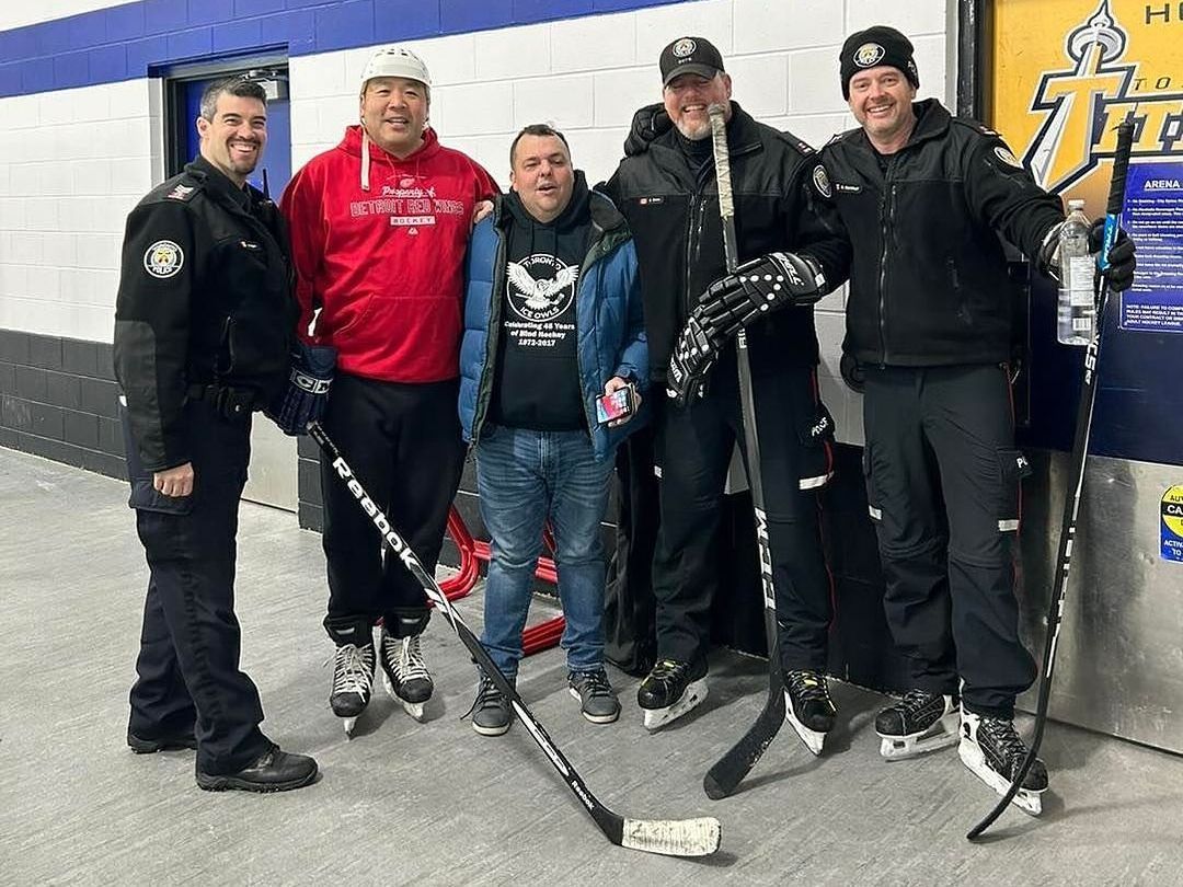 a group of men are posing for a picture while holding hockey sticks.