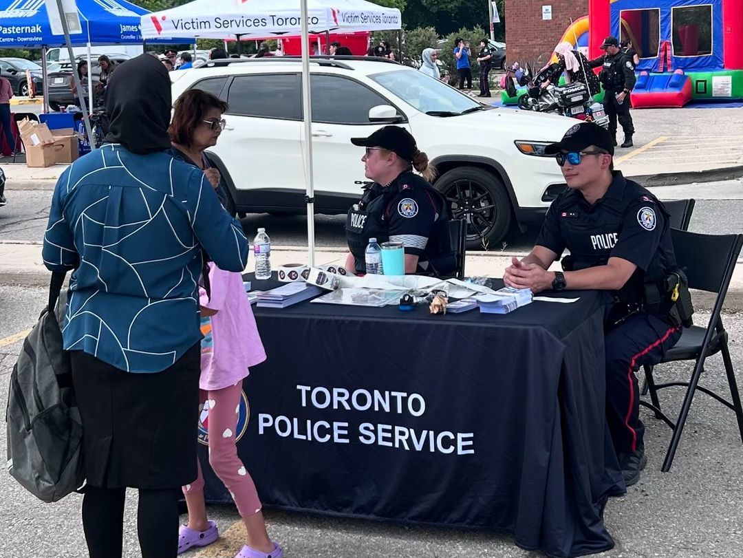 A group of police officers are sitting at a table talking to people.