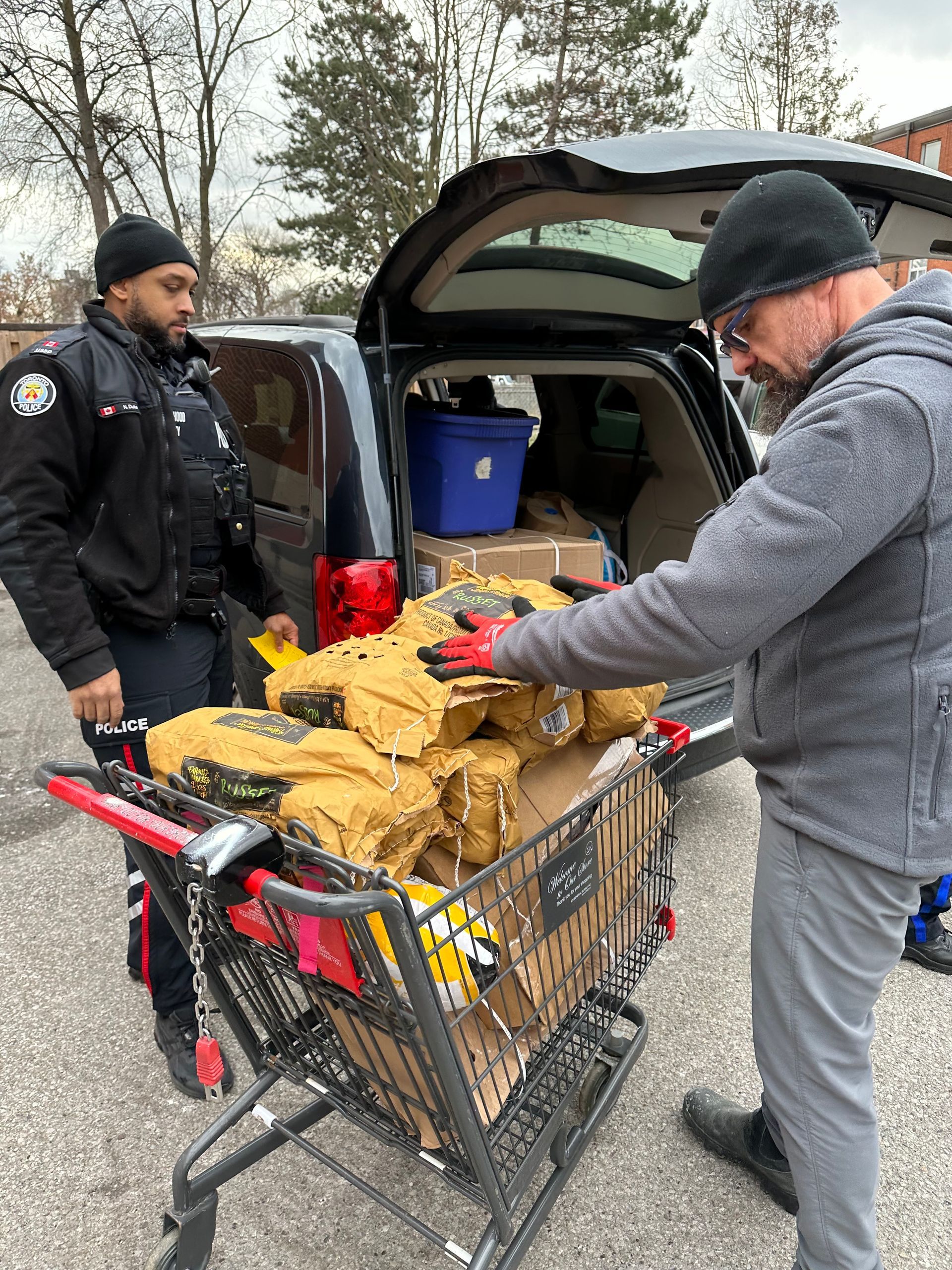 a man in a police uniform pushes a shopping cart full of boxes