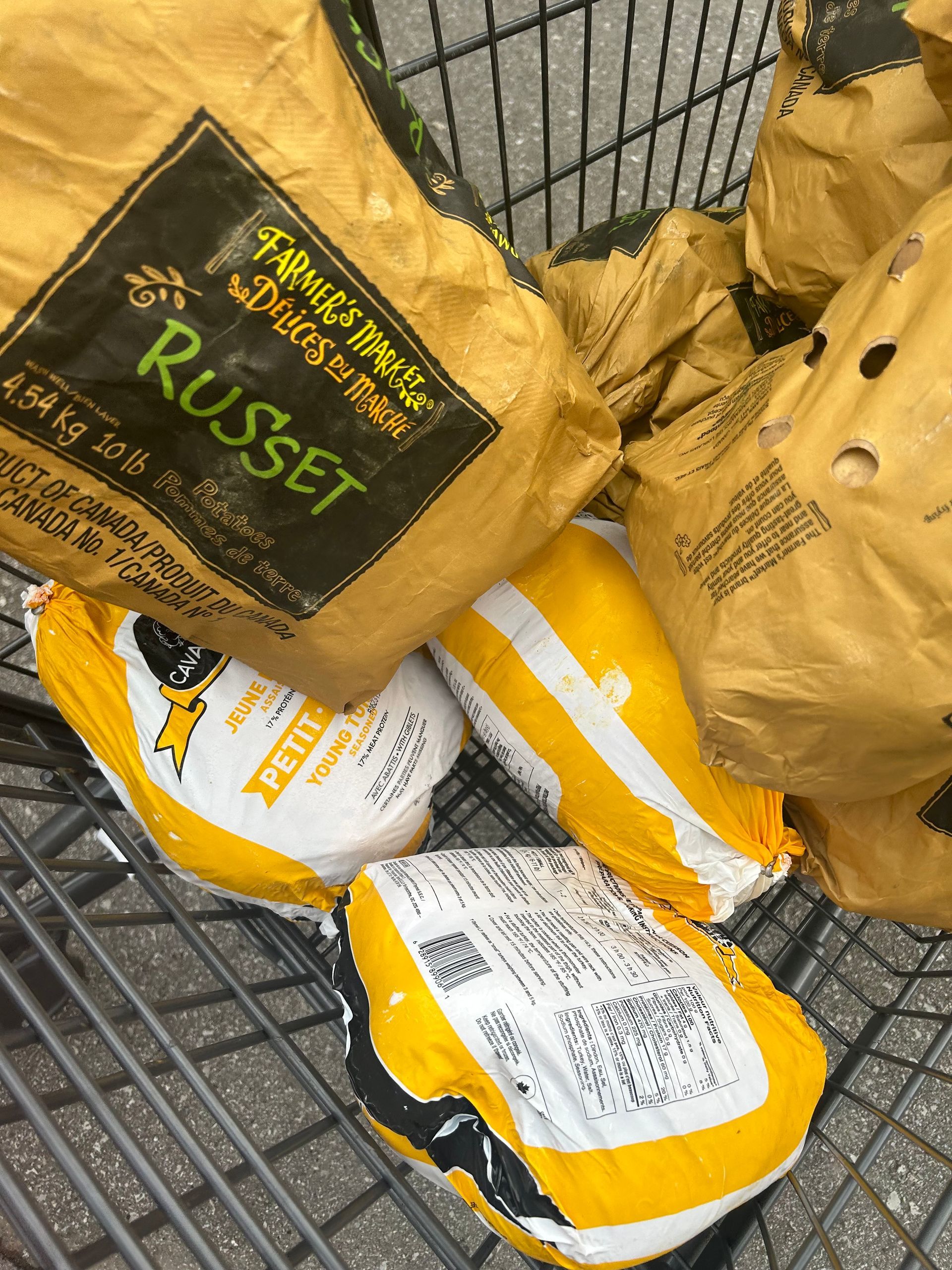 several bags of chicken and potatoes are in a shopping cart