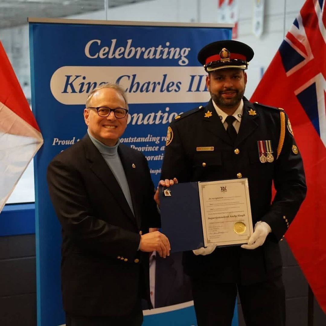 two men shaking hands in front of a banner that says celebrating King Charles III