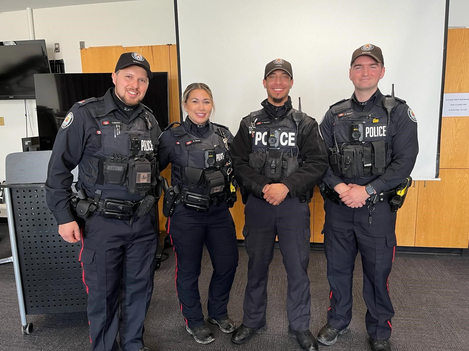 A group of police officers are posing for a picture in a room.