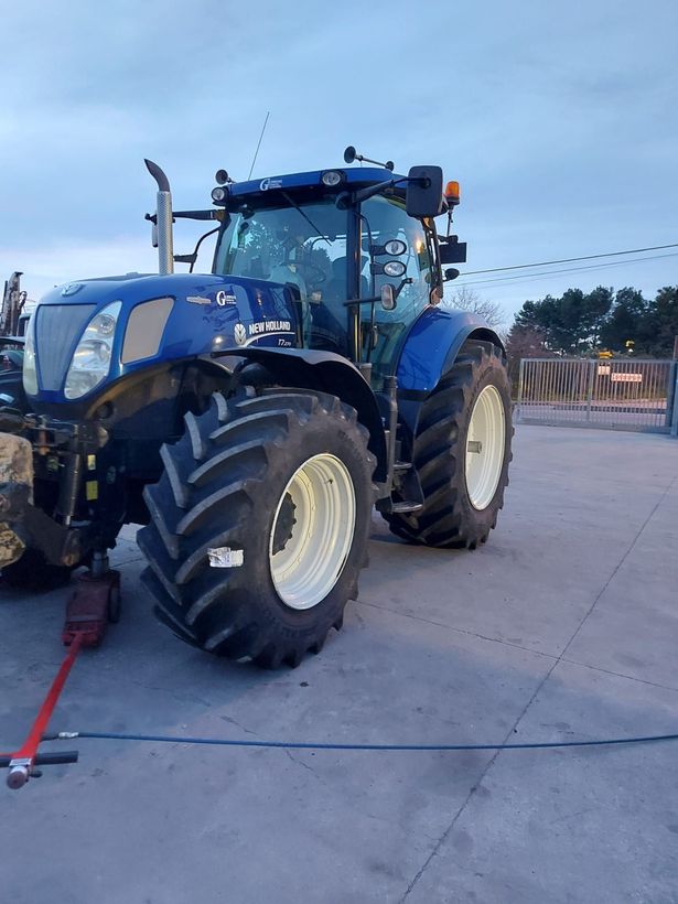 In un piazzale industriale, sono impilati pneumatici per carichi pesanti, tra cui grandi pneumatici fuoristrada in primo piano.