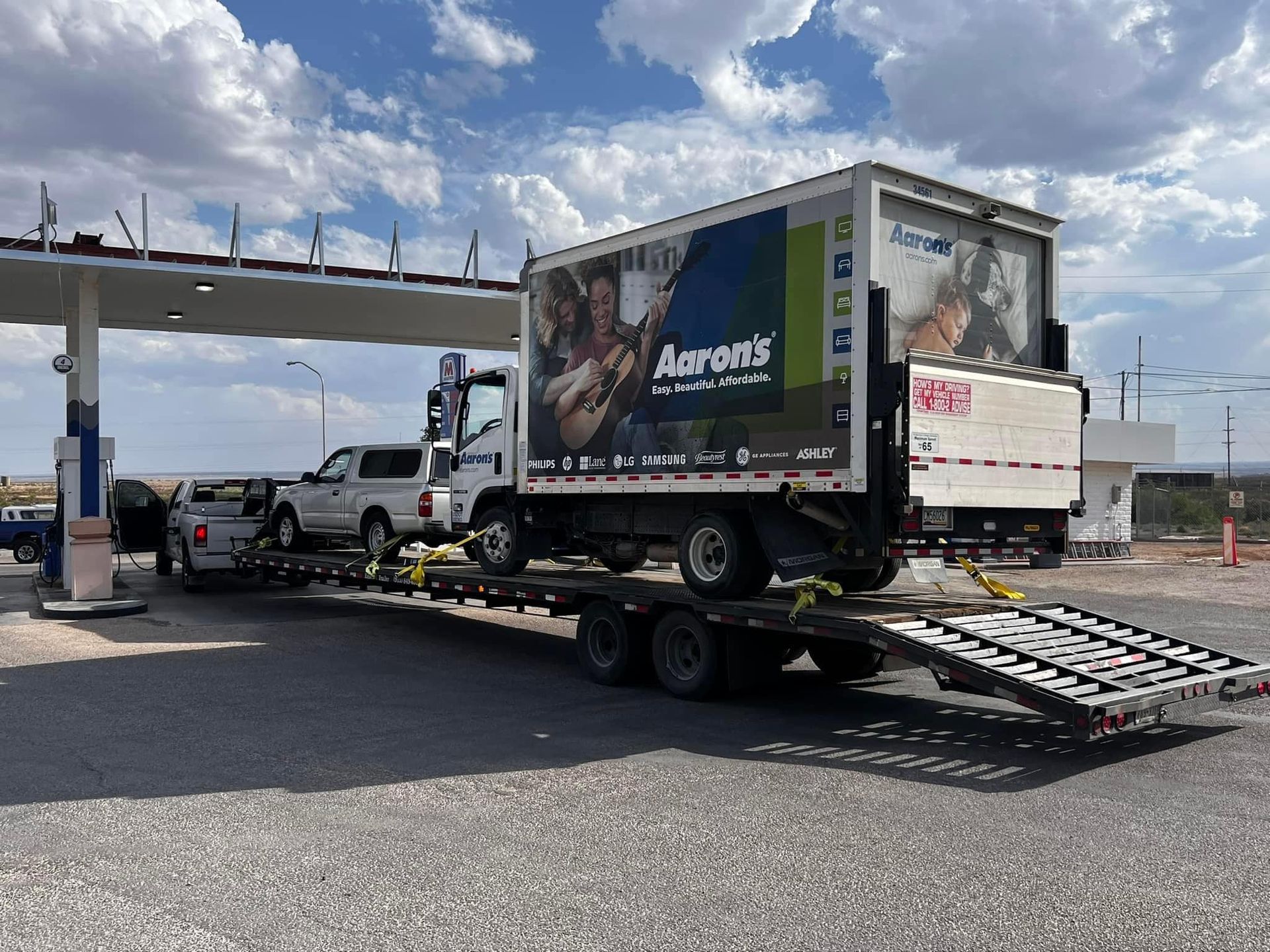 Truck on trailer at gas station, advertising 