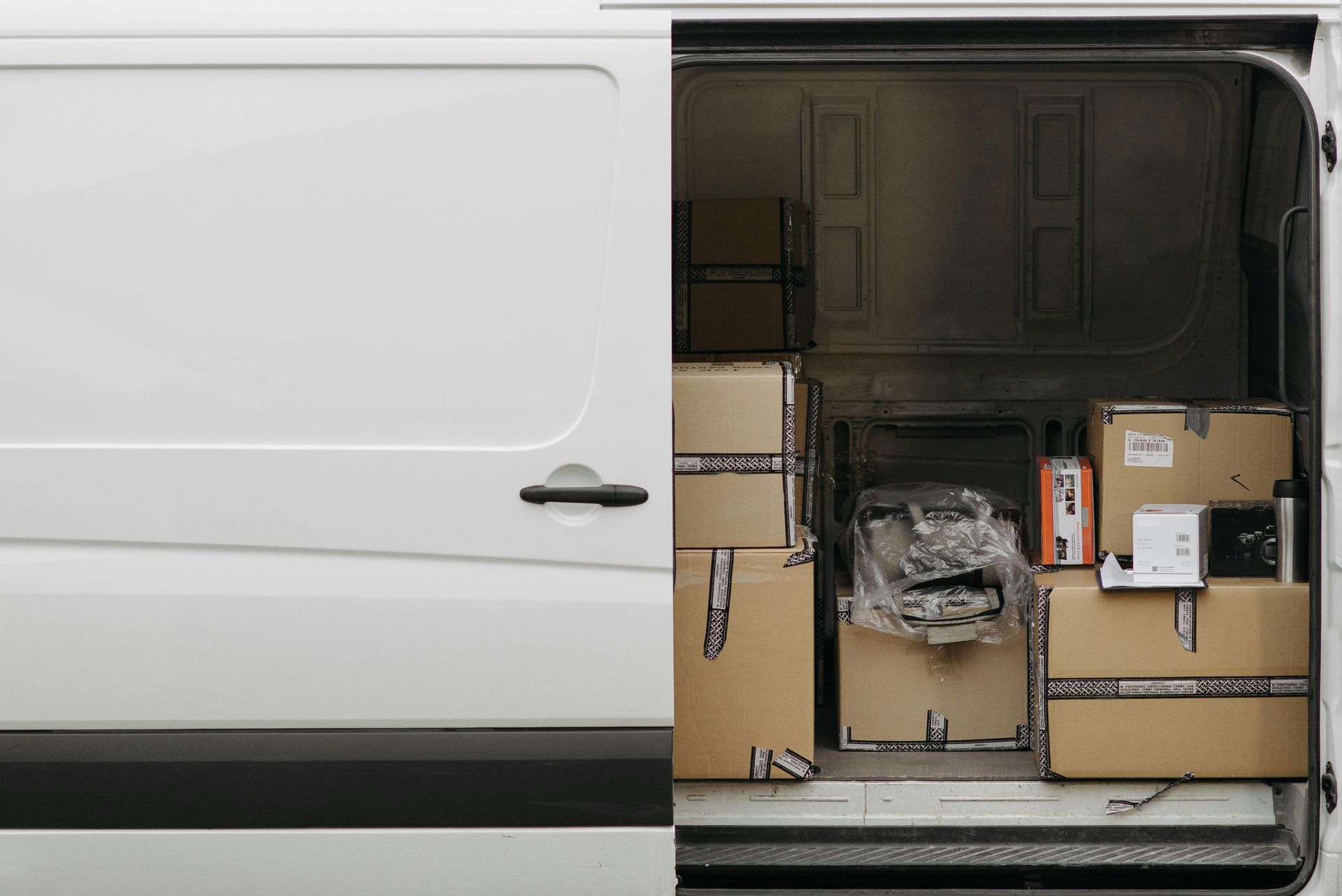 White delivery van with the cargo area open and loaded with cardboard boxes.