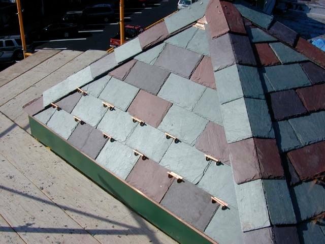 Colorful shingled roof with patchwork panels and visible fasteners, photographed outdoors from above