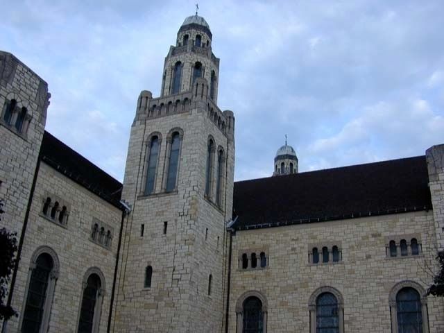 Stone church tower and building under a cloudy sky